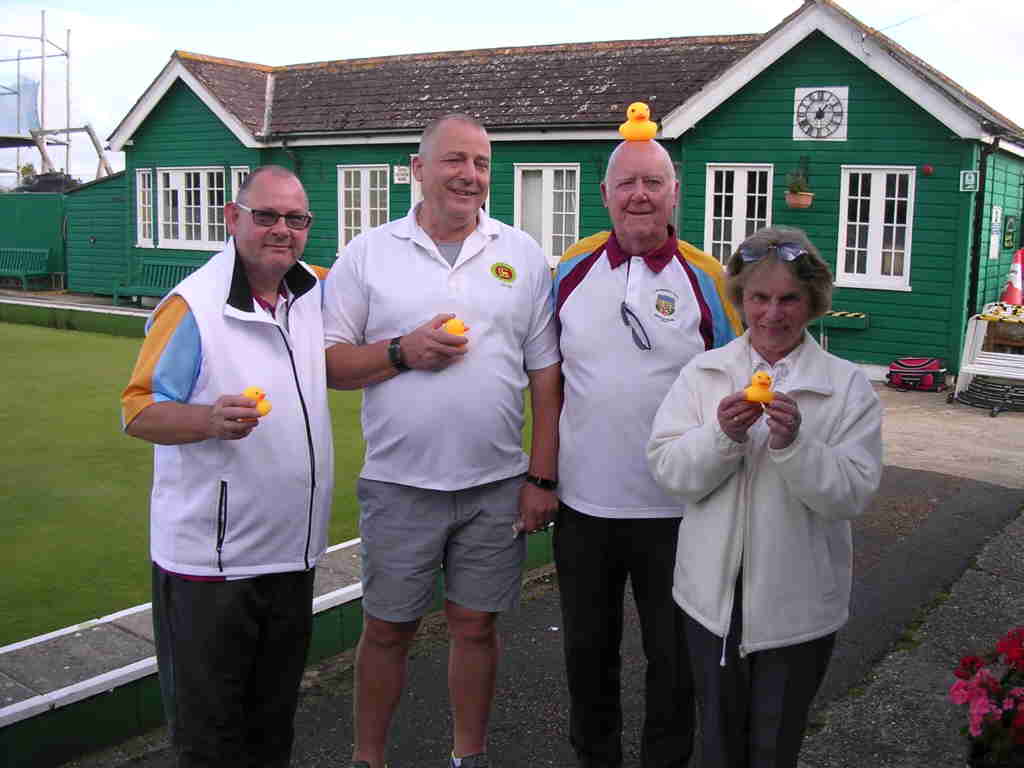 four bowlers holding small rubber ducks