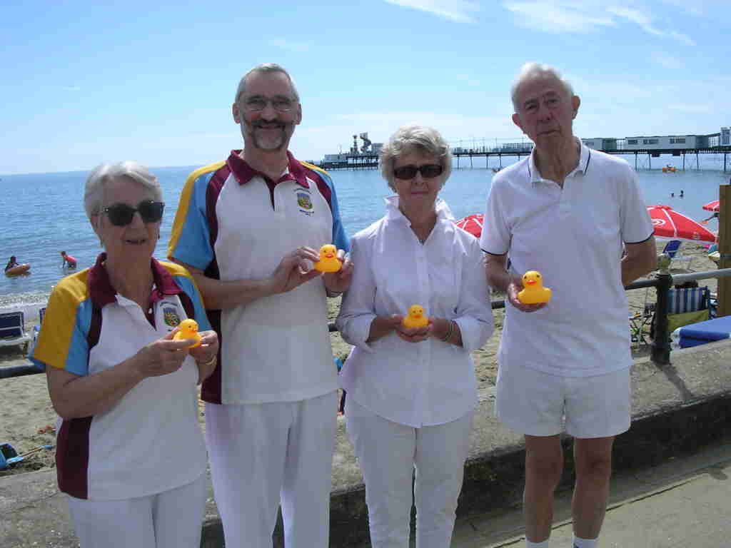 four bowlers holding small rubber ducks
