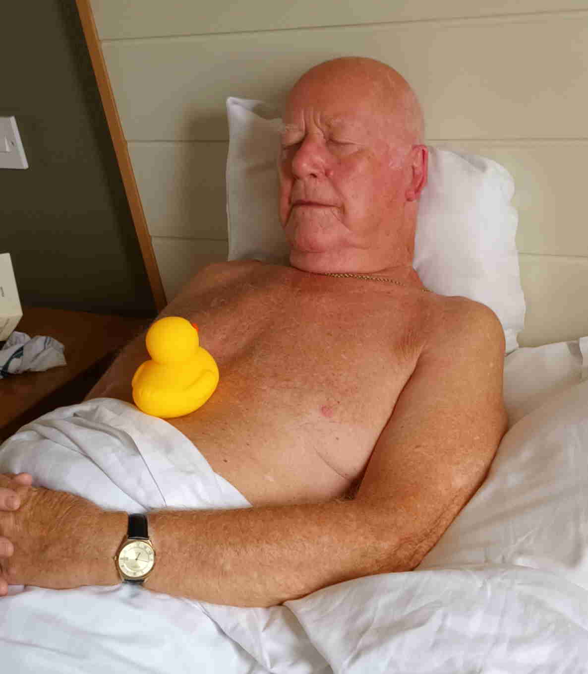 man in bed asleep with a rubber duck on his chest